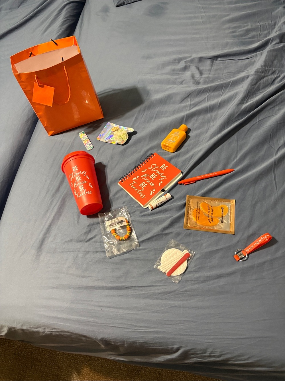 orange bag with cup, notebook, keychain, pen, jewelry. Lip balm, lotion, etc.